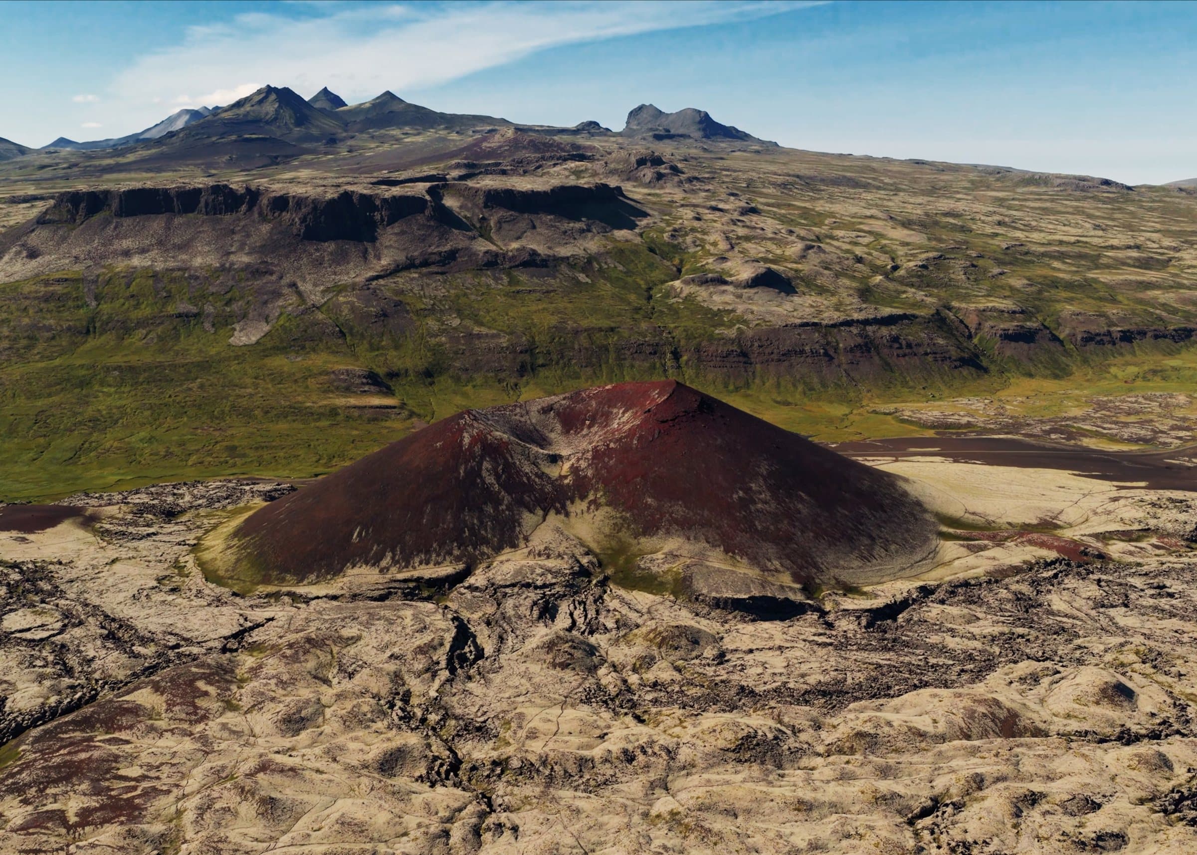 Aerial view of a red volcanic cone in a green valley, Iceland.
