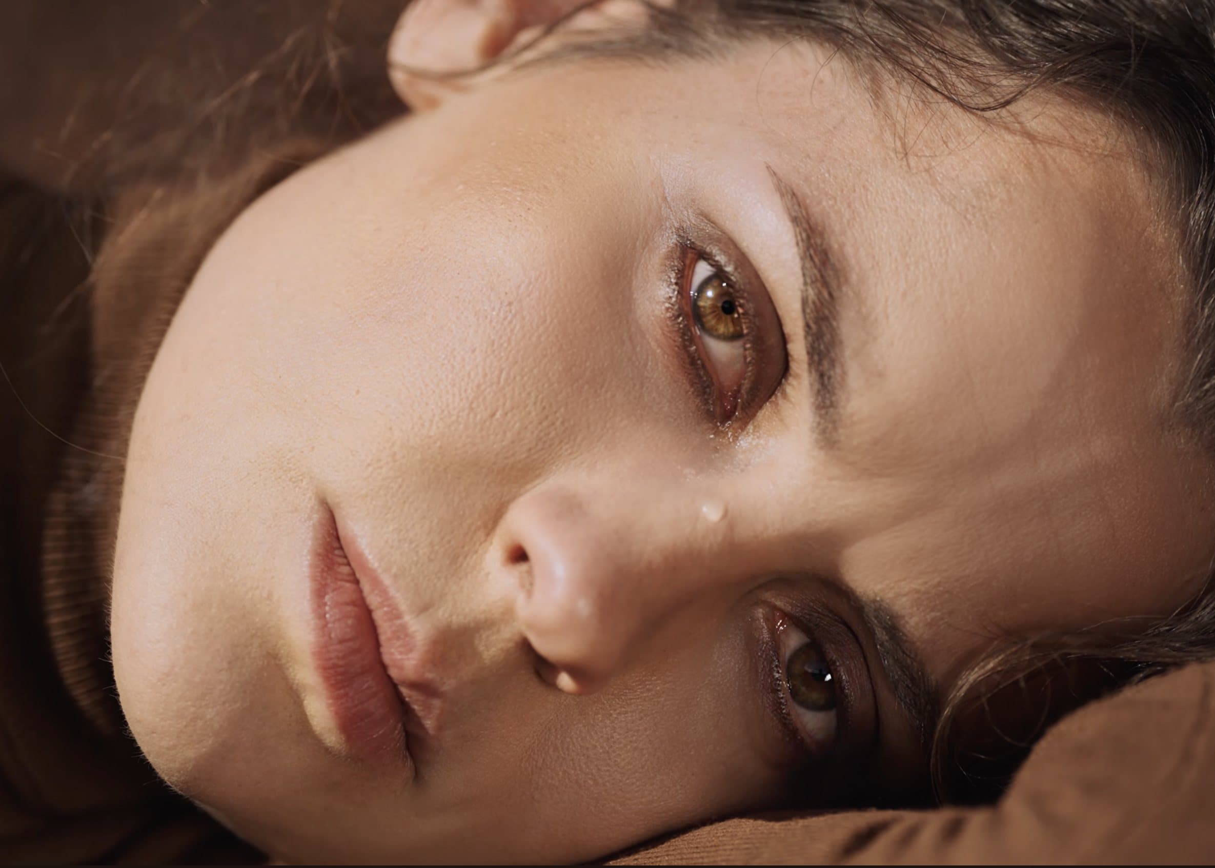 Close-up of a woman resting her head and looking into the lens.